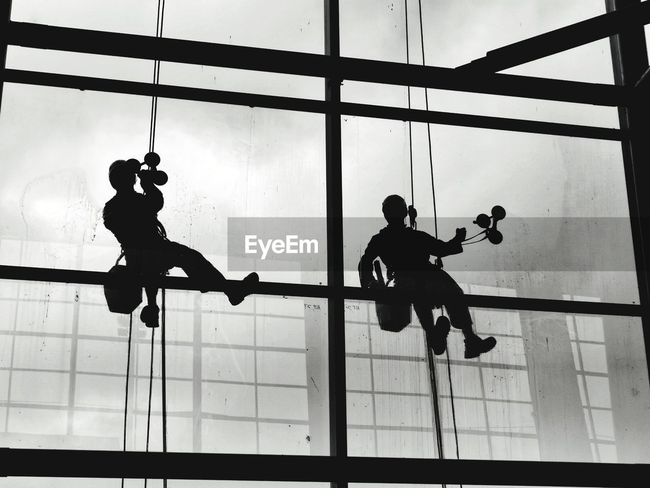 LOW ANGLE VIEW OF SILHOUETTE PEOPLE AT GLASS WINDOW