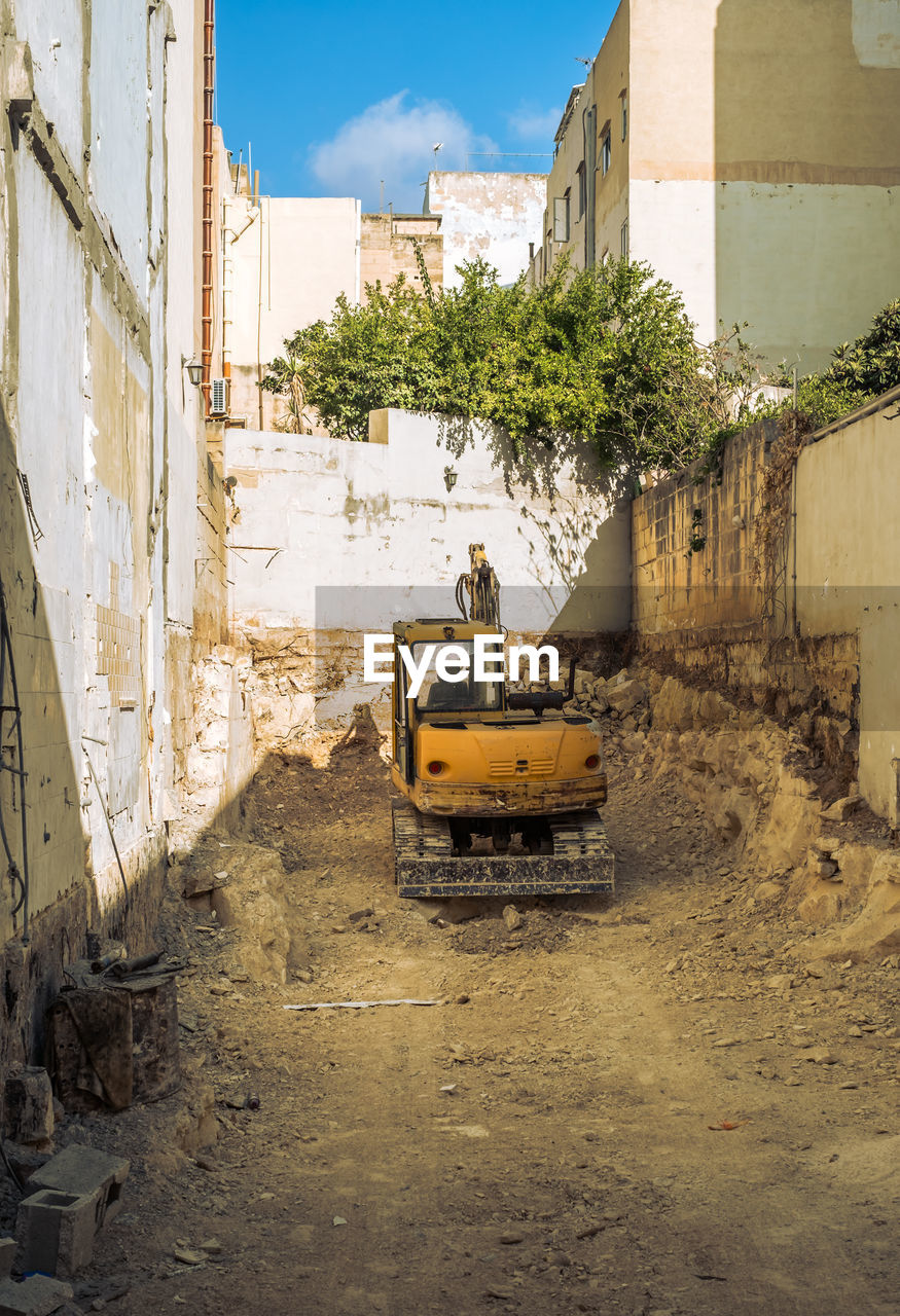 A yellow excavator digs the foundation of a building