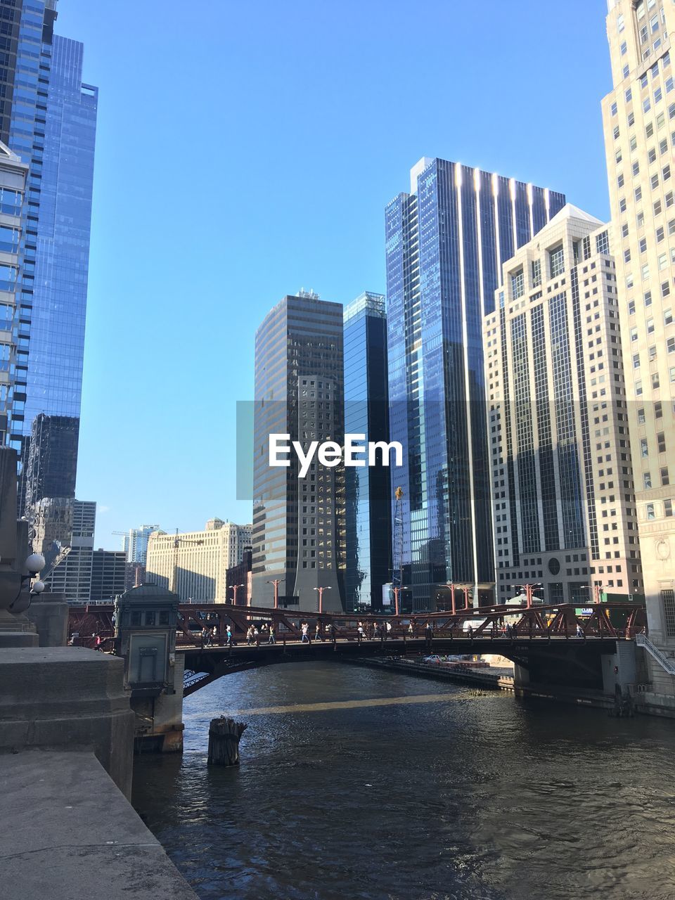 BRIDGE OVER RIVER BY BUILDINGS AGAINST CLEAR SKY