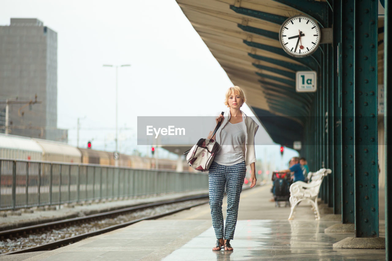 Full length portrait of woman standing on railroad station