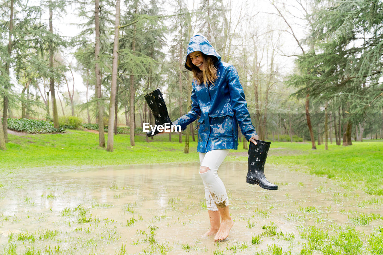 Full length of woman enjoying in puddle at park