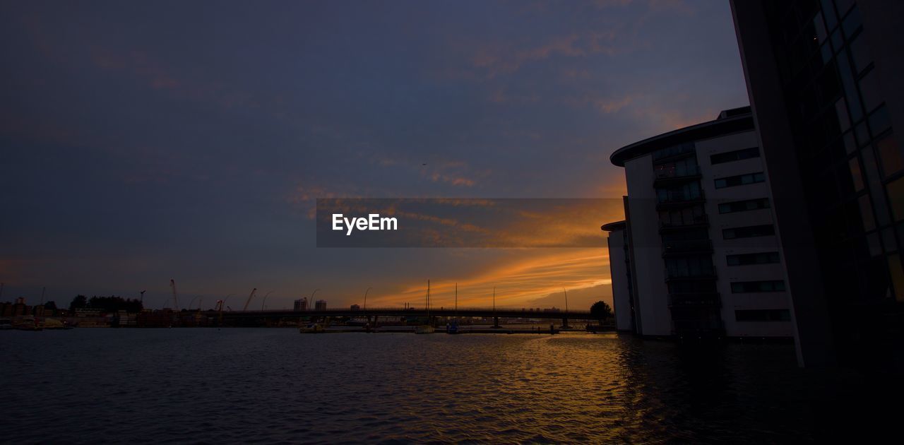 BUILDINGS BY SEA AGAINST SKY DURING SUNSET