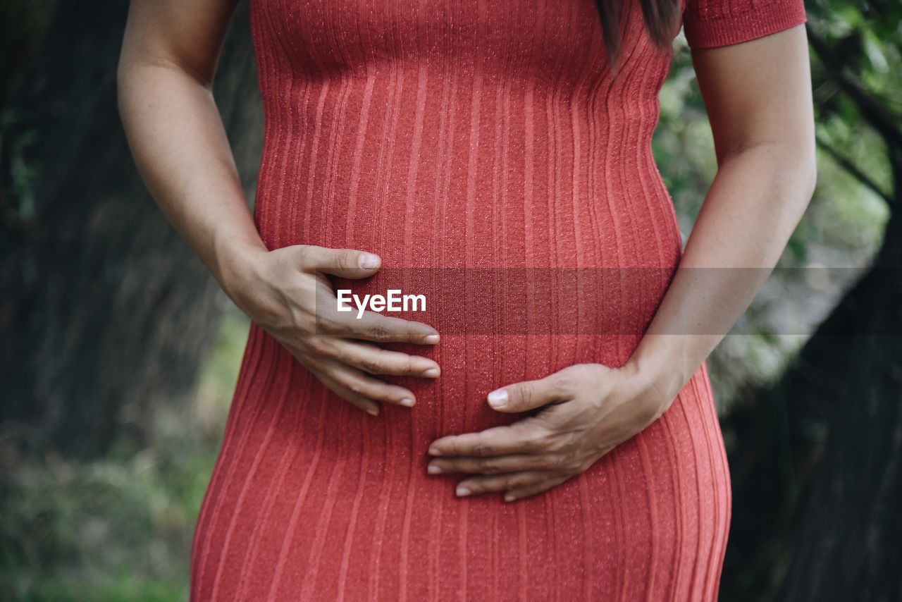 Midsection of pregnant woman standing  outdoors