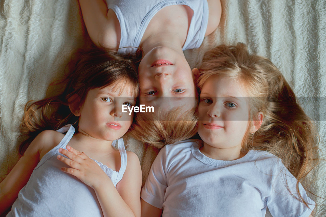 High angle portrait of cute siblings lying on bed at home