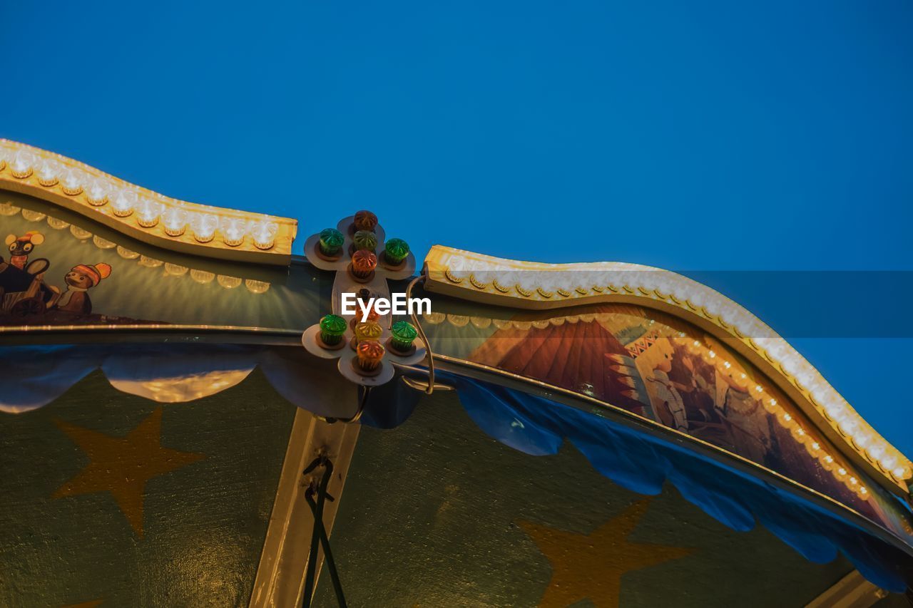 Cropped image of carousel against clear blue sky