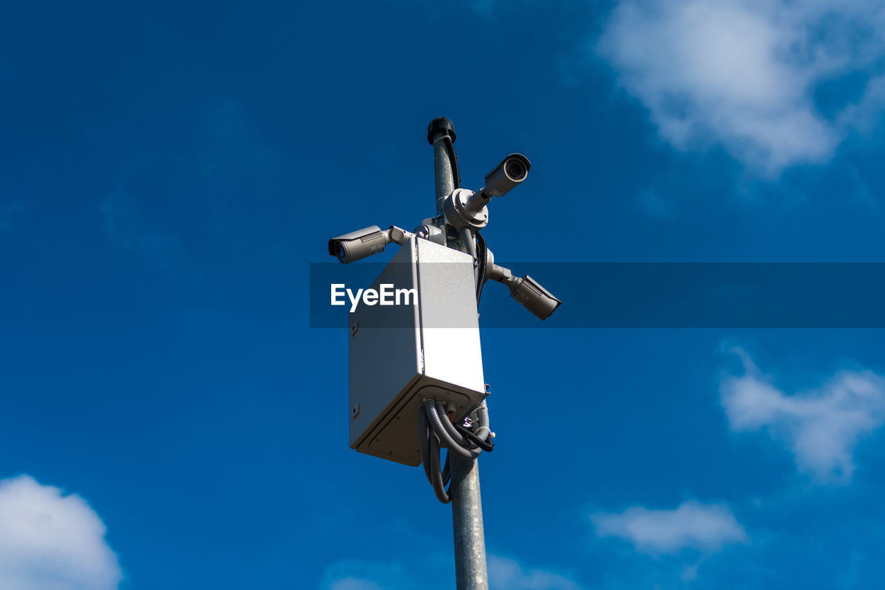 Low angle view of camera pole against blue sky