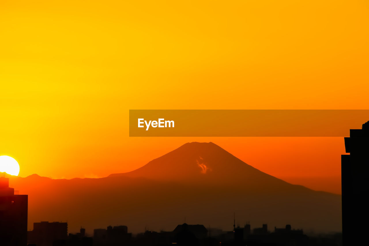 Silhouette buildings against orange sky