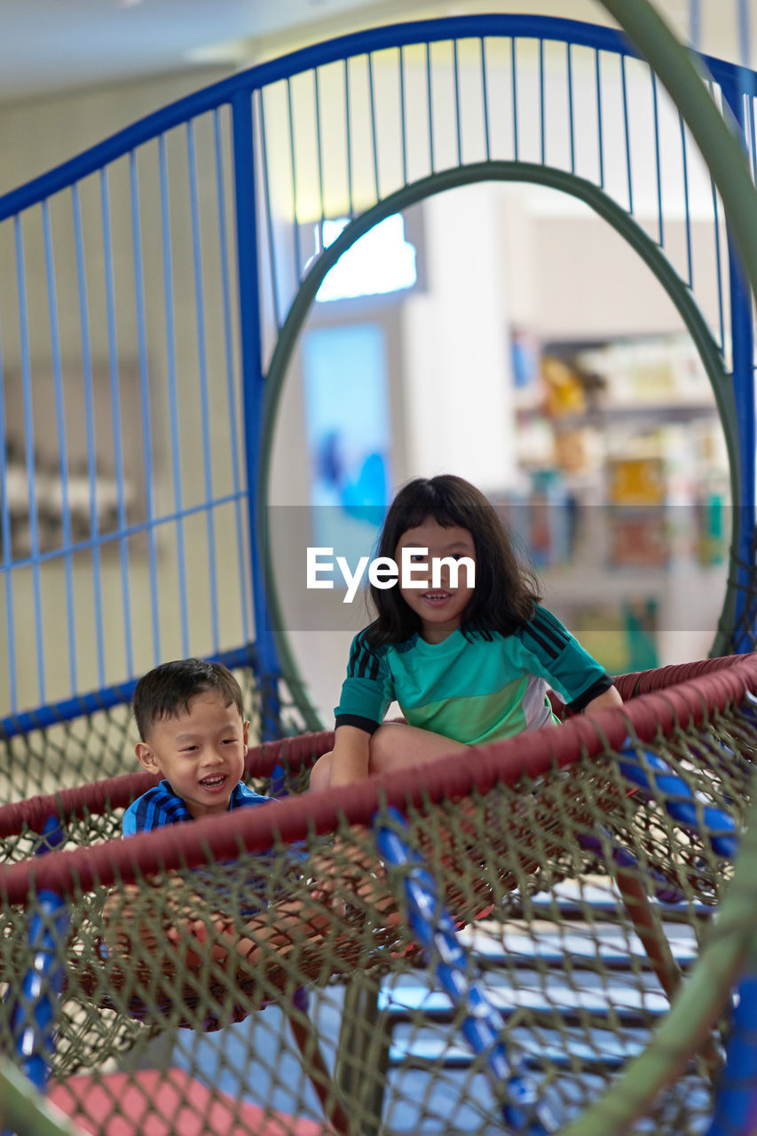 Siblings sitting on play equipment