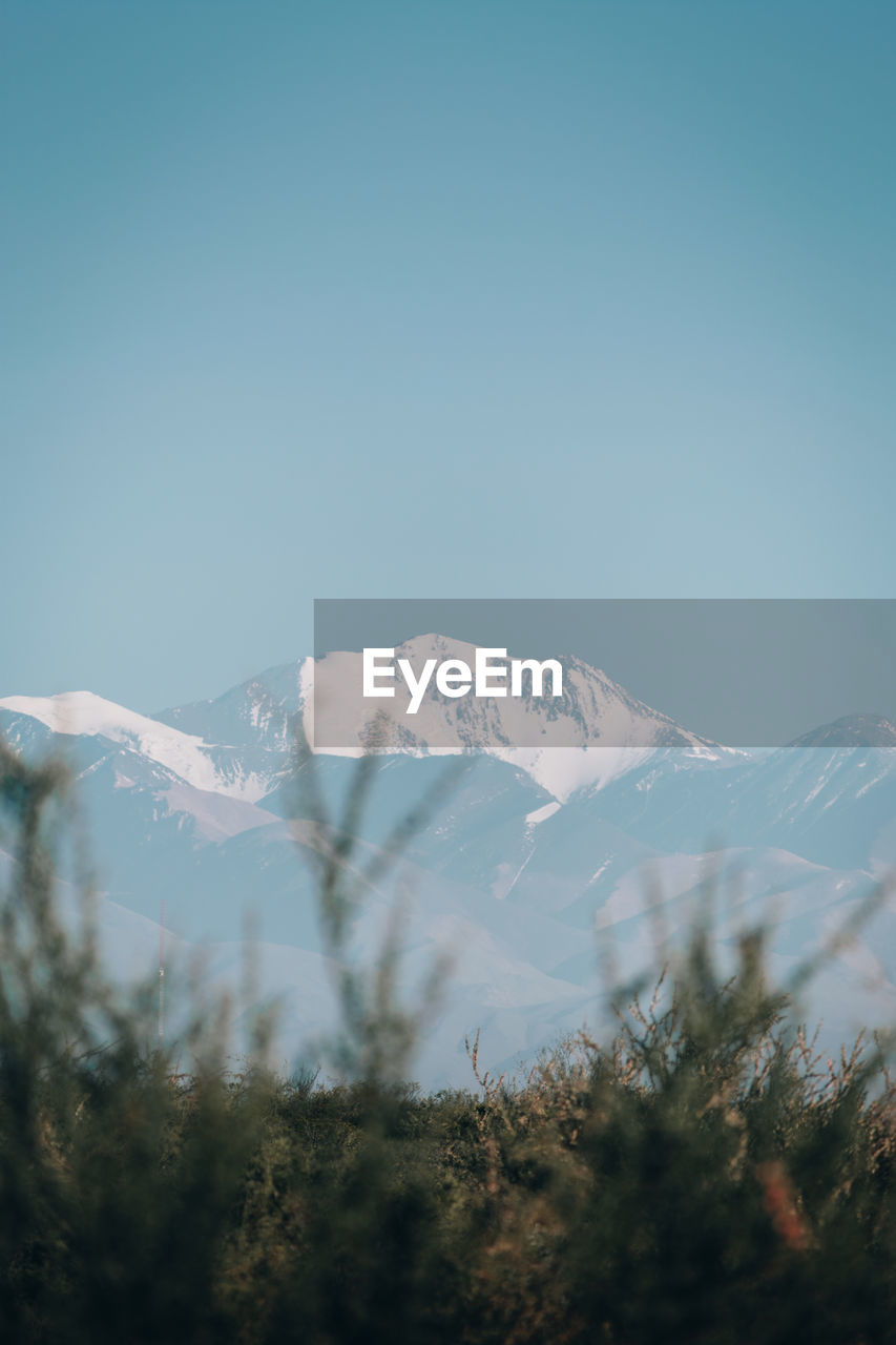 Scenic view of snowcapped mountains against clear blue sky