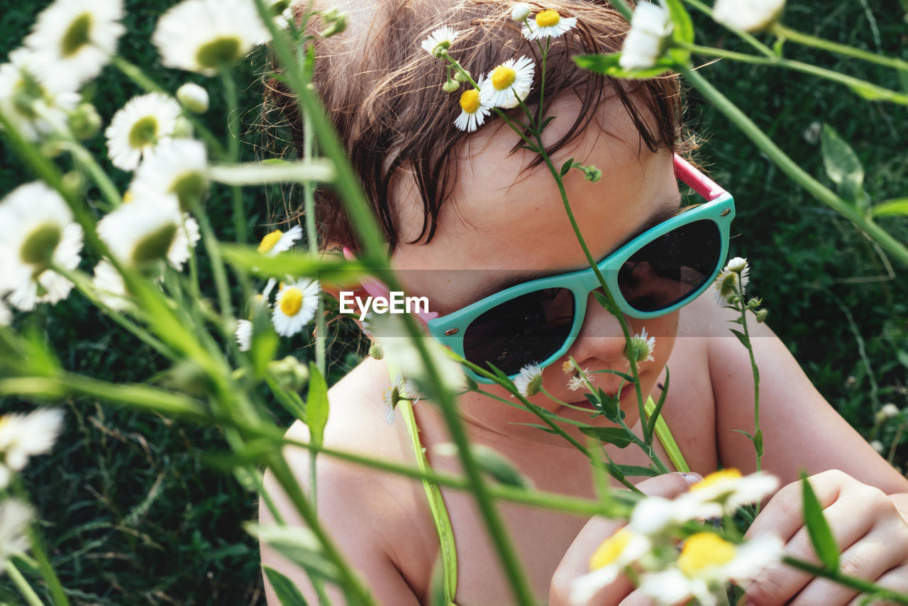 Portrait of a child in sunglasses in daisies flowers. girl sniffing chamomiles. summer time