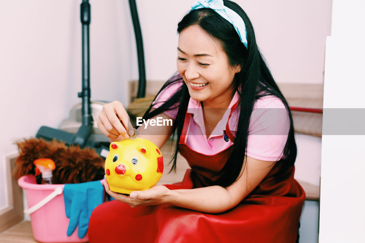 YOUNG WOMAN HOLDING A SMILING WHILE SITTING IN THE ROOM