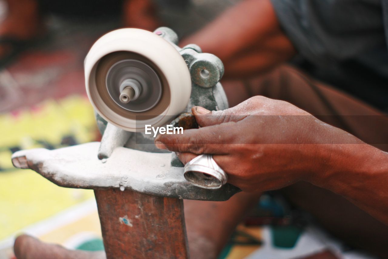 Low section of man polishing gemstone in workshop