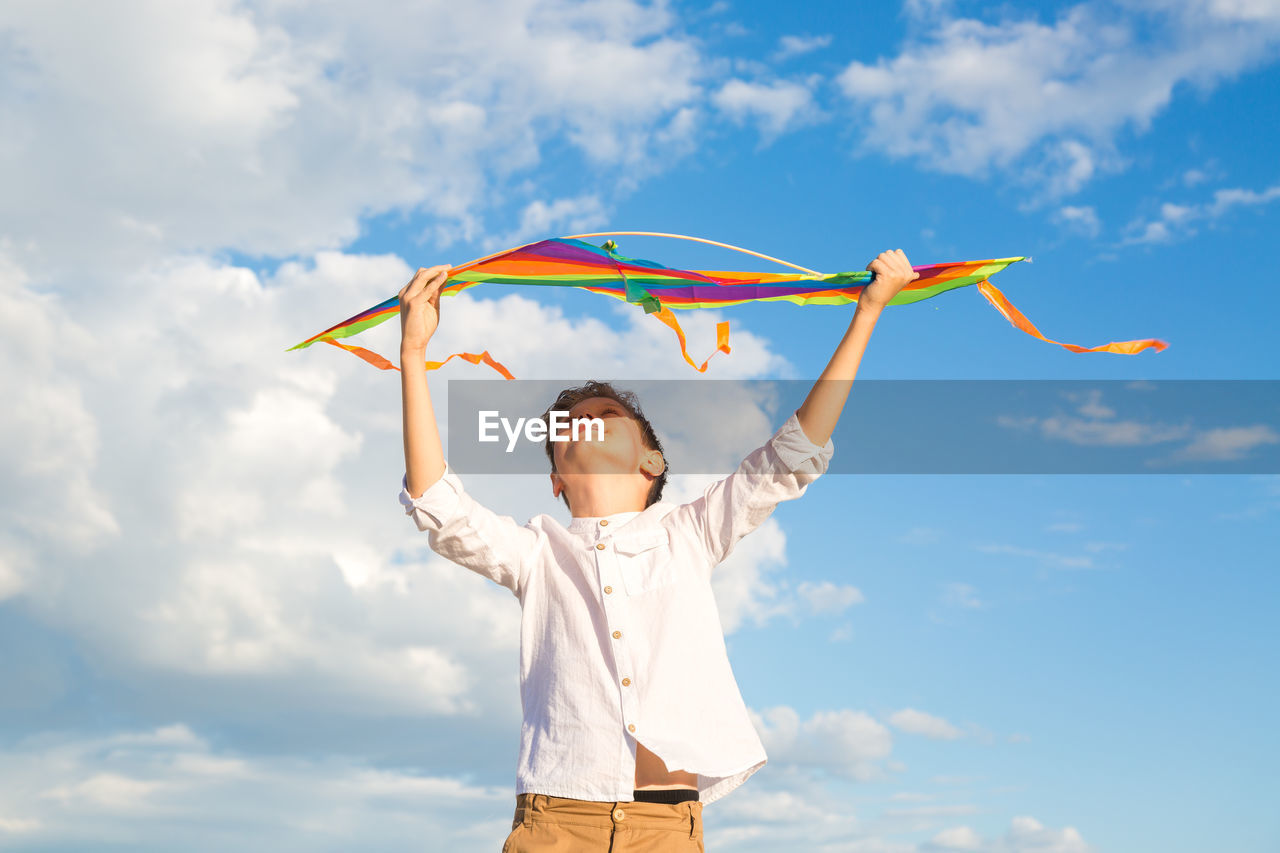 A 9-year-old boy with a bright colorful kite stands high mountain against a background of beautiful 