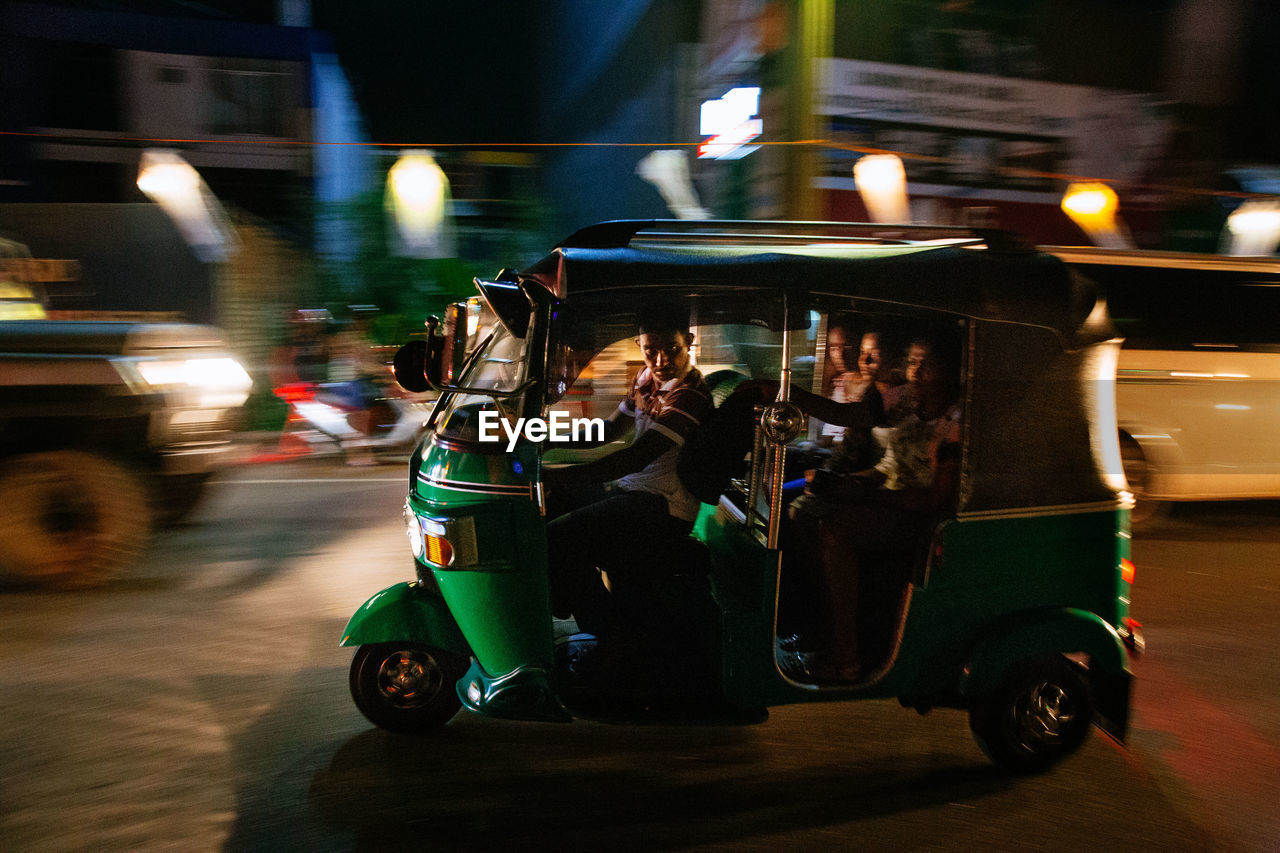 CARS ON ILLUMINATED CITY STREET AT NIGHT