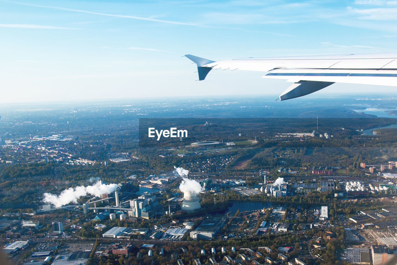 Cropped image of aircraft wing over city against sky