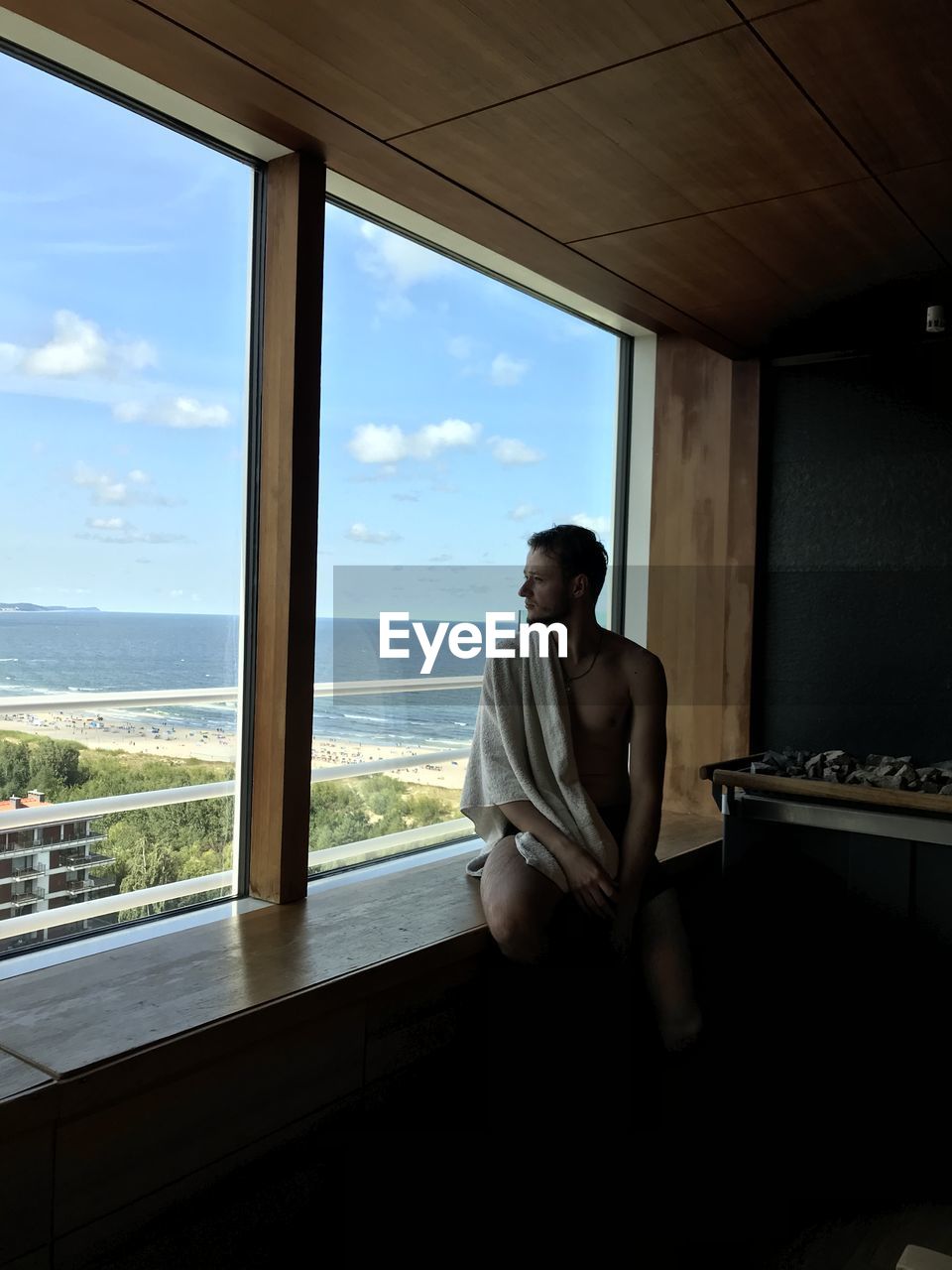 YOUNG MAN LOOKING THROUGH WINDOW AT VIEW