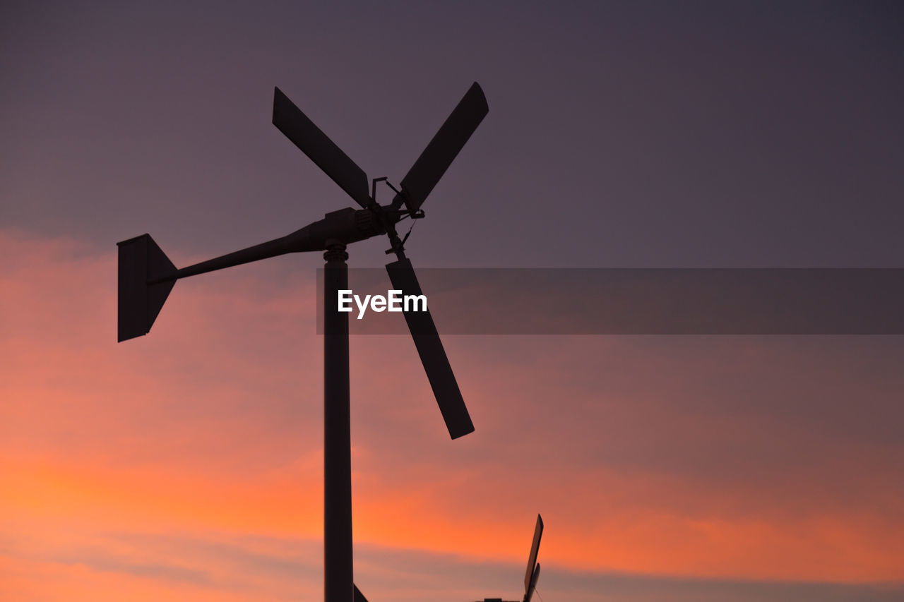 low angle view of windmill against orange sky