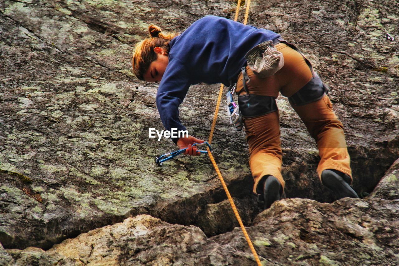 Full length of woman climbing on rock