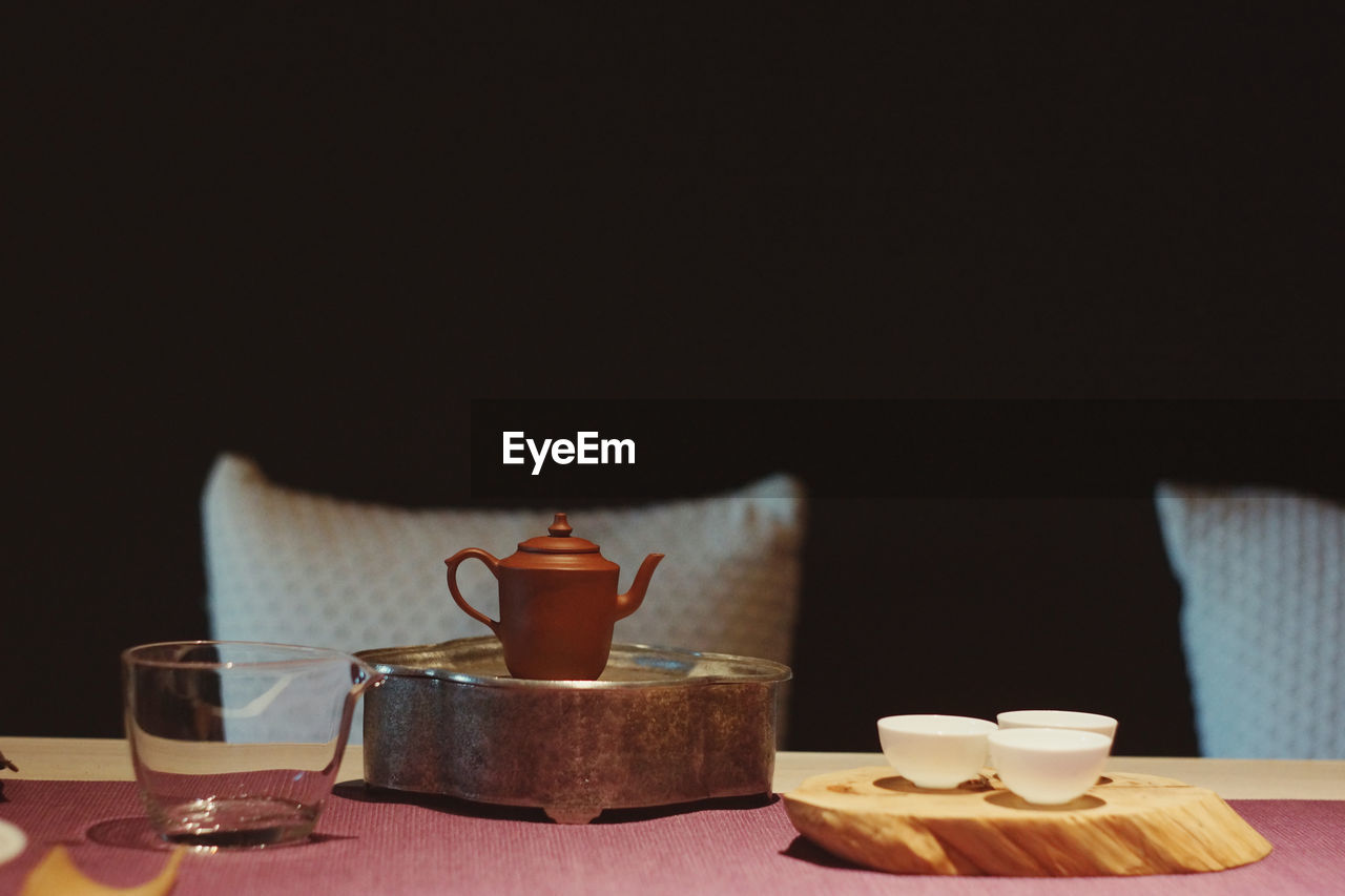 CLOSE-UP OF COFFEE CUP ON TABLE AGAINST BLACK BACKGROUND