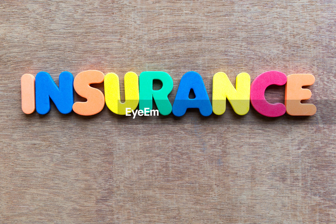 High angle view of colorful insurance text on wooden table