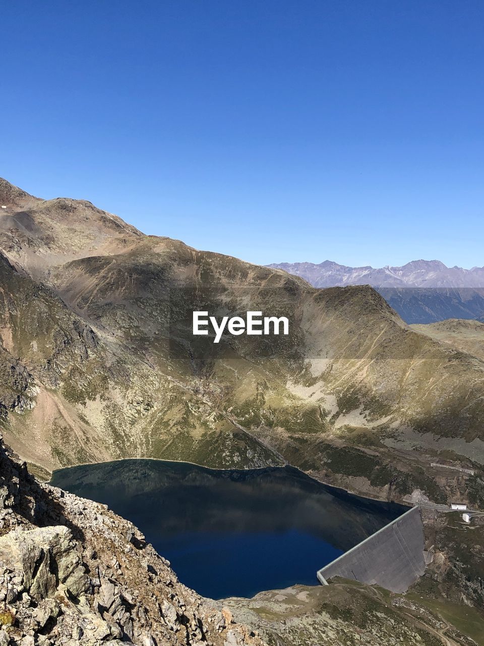 Scenic view of lake and mountains against clear blue sky