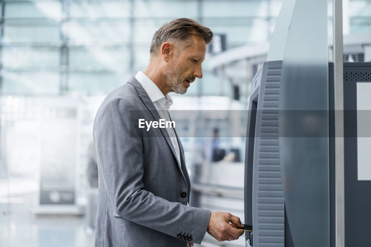 Mature businessman inserting credit card in atm machine