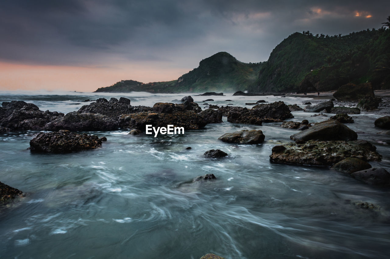 ROCKS IN SEA AGAINST SKY DURING SUNSET