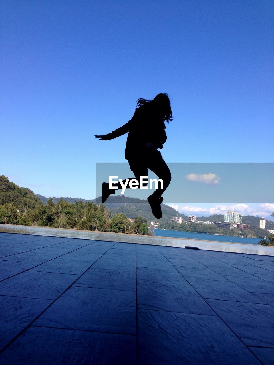 Silhouette woman jumping against blue sky