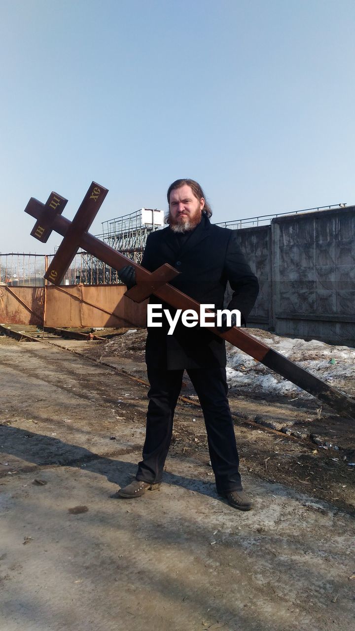 Full length portrait of man holding cross