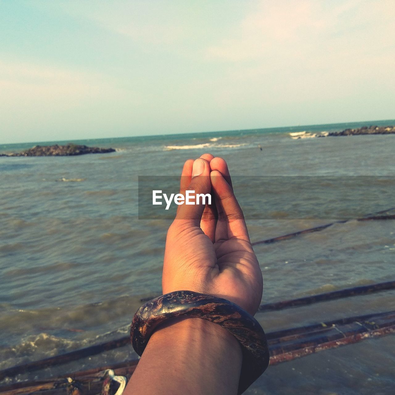 MIDSECTION OF HAND ON SEA SHORE
