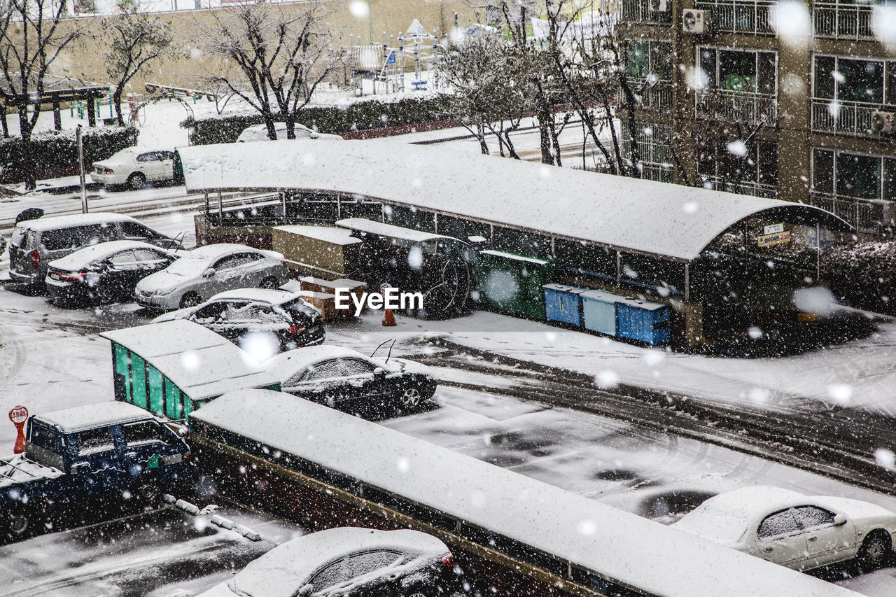 High angle view of snow covered vehicles parked at parking lot