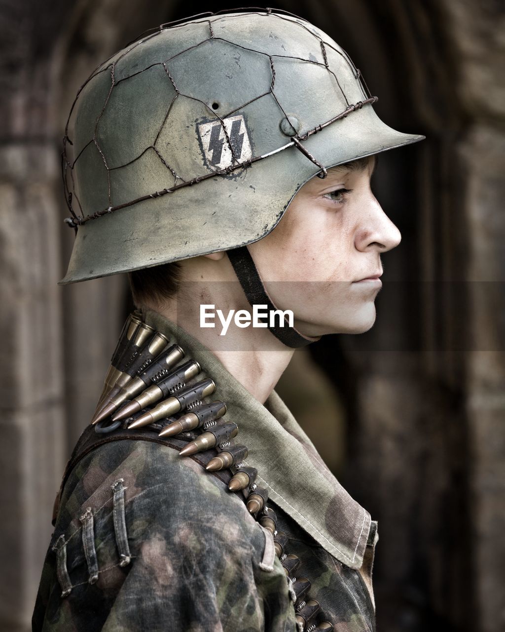 Profile view of young soldier wearing helmet and bullets