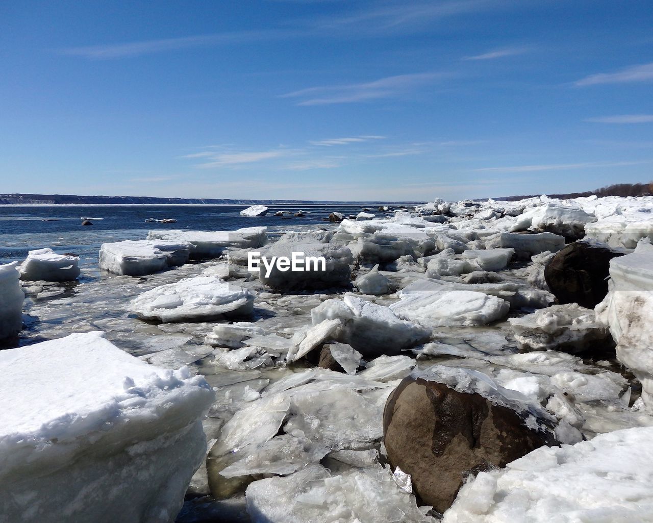 Icebergs at frozen lake against sky