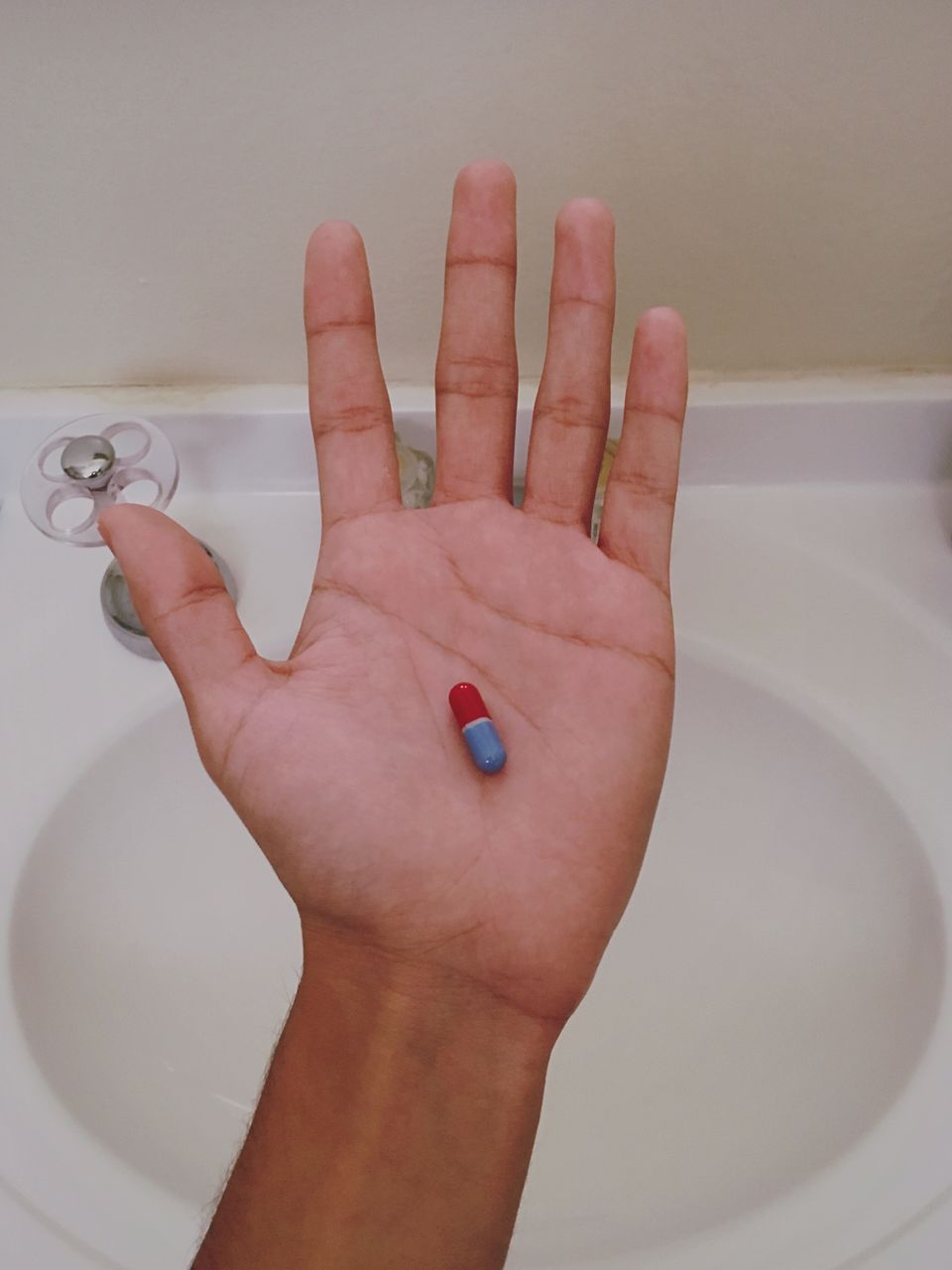Human hand holding pill in bathroom