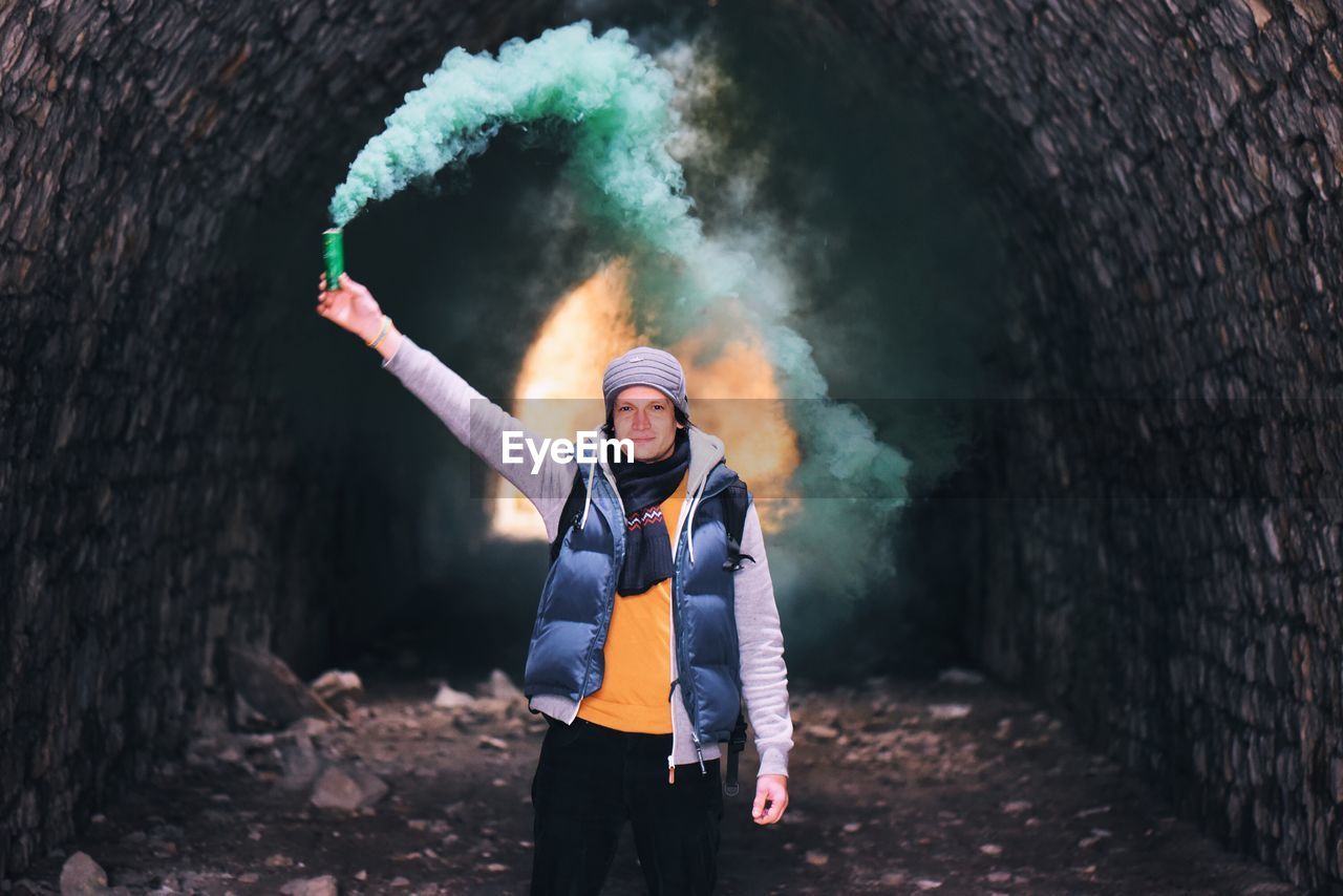 Portrait of young man holding flare in cave