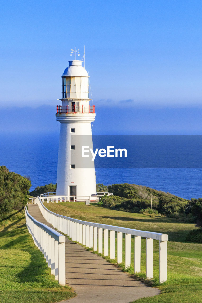 Lighthouse by sea against sky