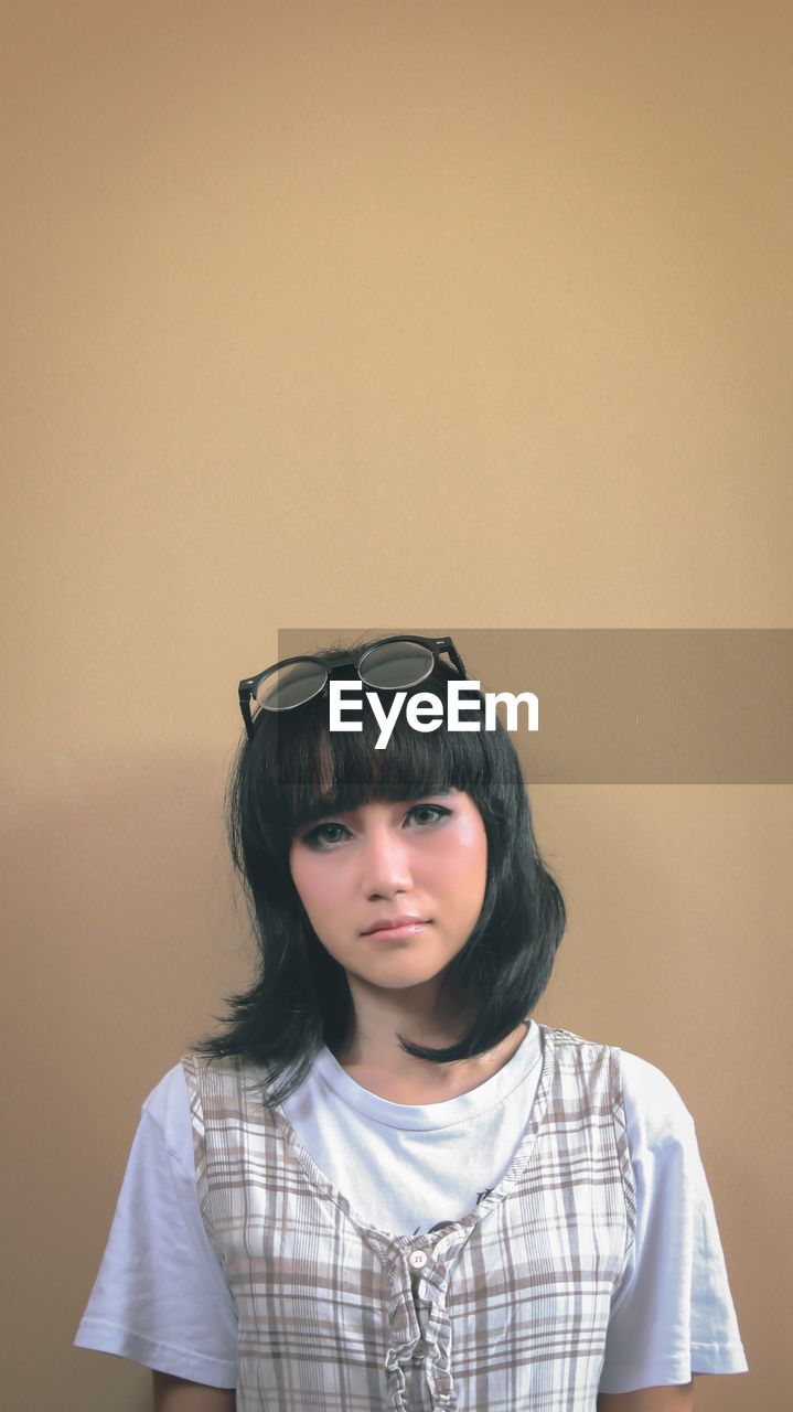 Portrait of young woman against beige background