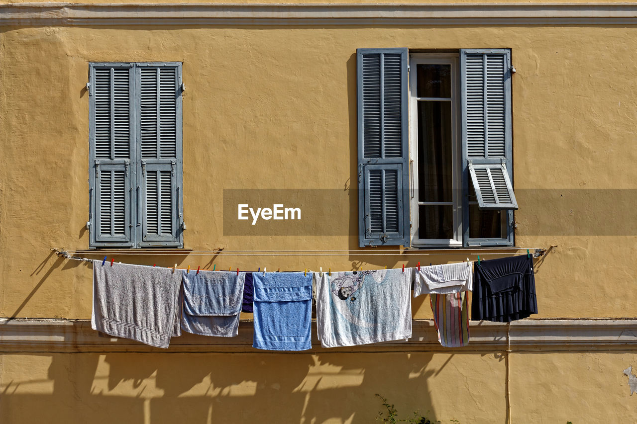 LOW ANGLE VIEW OF CLOTHES DRYING AGAINST WINDOW