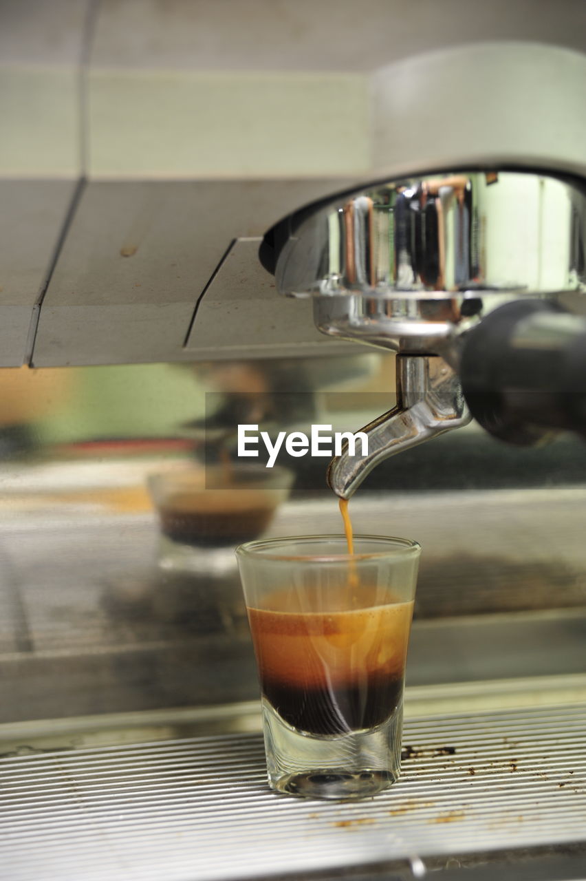 Close-up of coffee pouring in glass at cafe