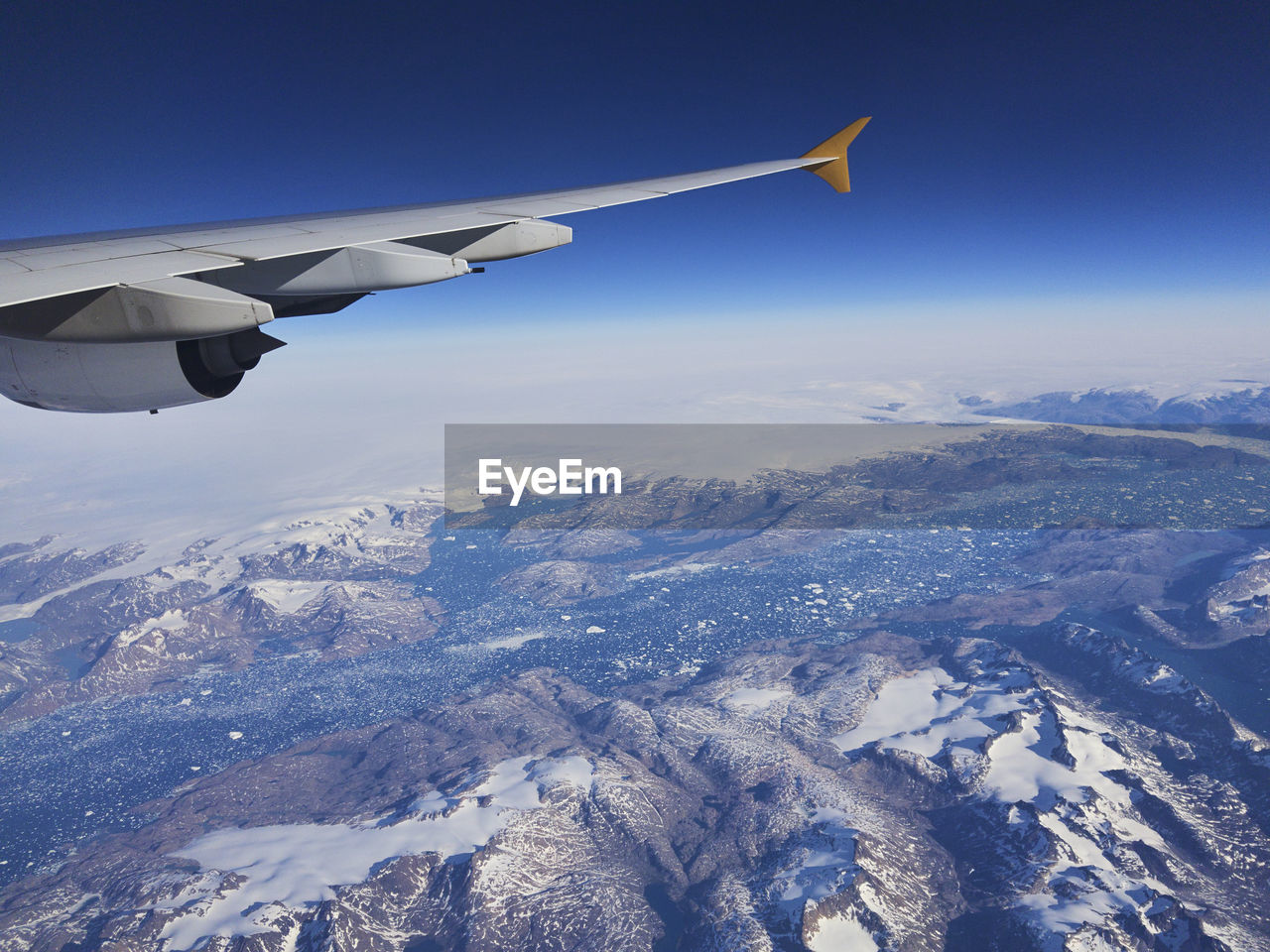 AERIAL VIEW OF AIRPLANE FLYING OVER MOUNTAINS