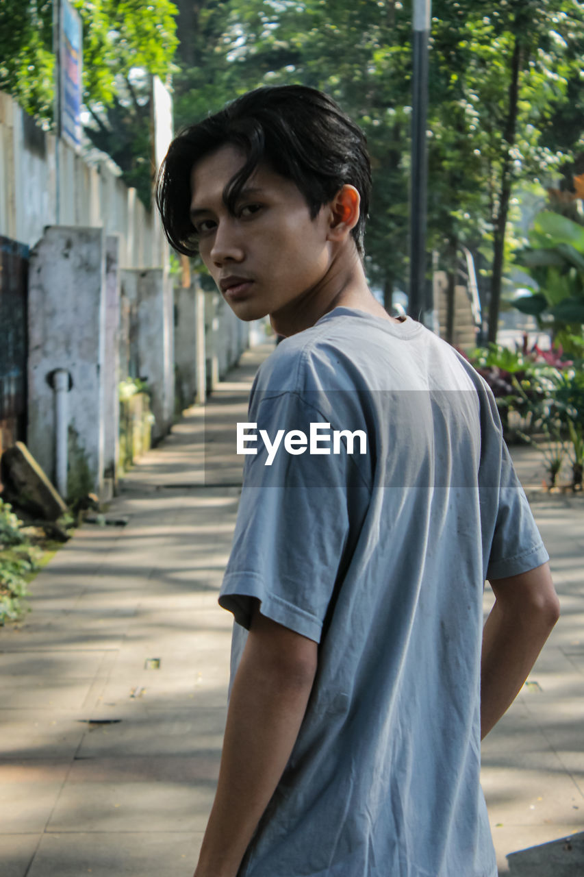 Side view of young man looking away while standing outdoors