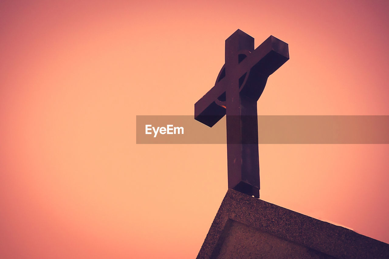 LOW ANGLE VIEW OF CROSS AGAINST BUILDING DURING SUNSET