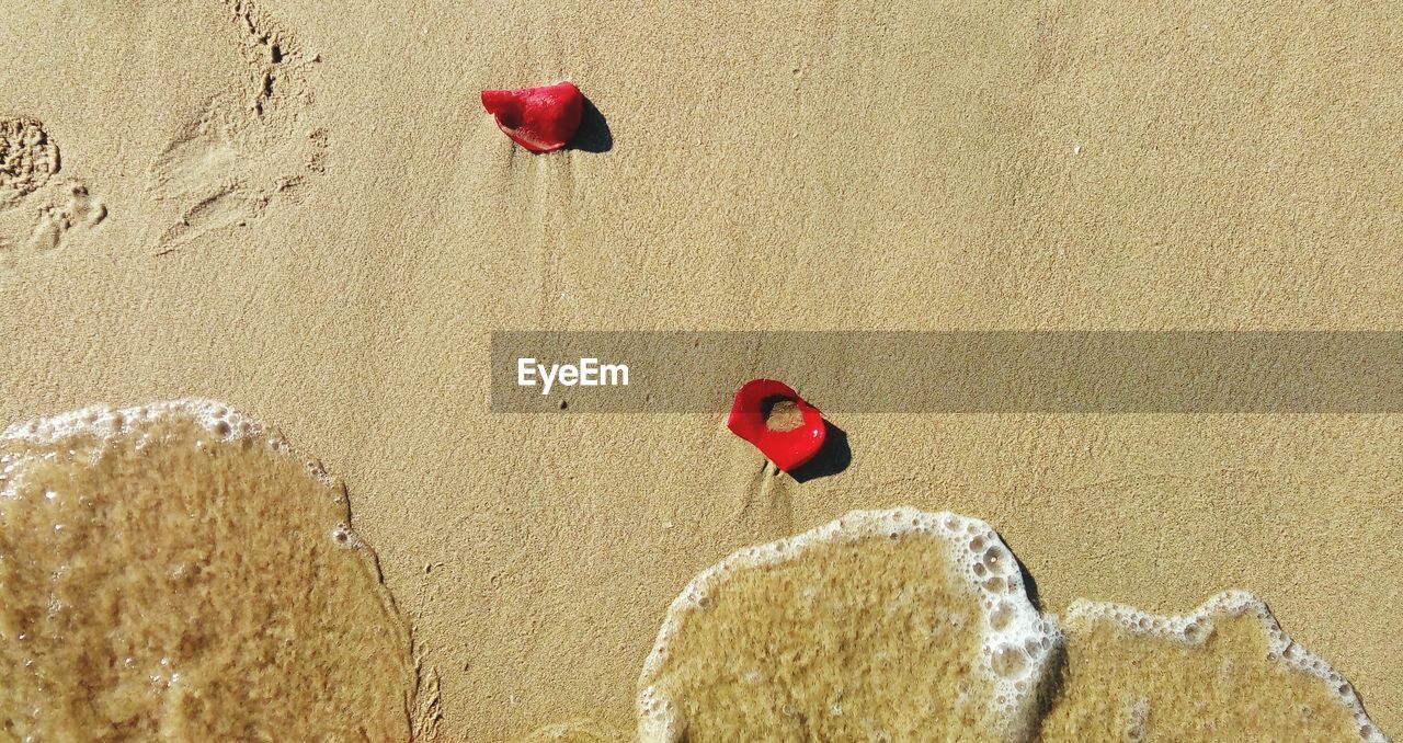 CLOSE-UP OF RED HEART SHAPE ON SAND