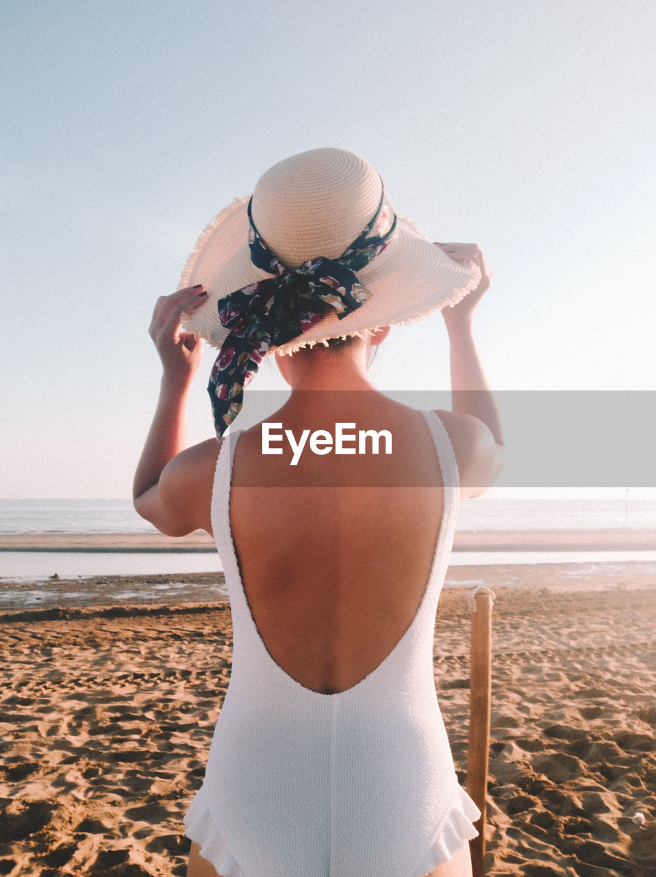 REAR VIEW OF WOMAN STANDING AT BEACH