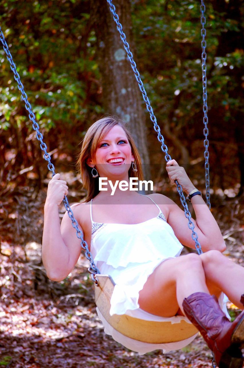 Portrait of a smiling young woman on swing