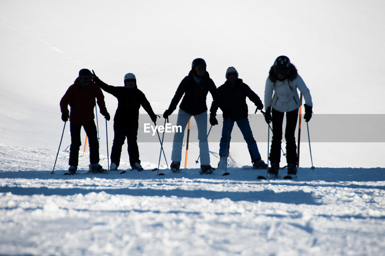 Rear view of friends skiing on snow covered landscape during winter