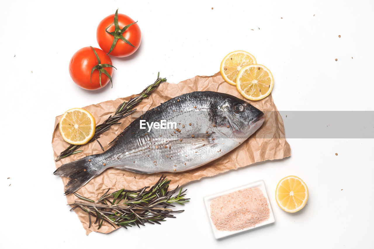 HIGH ANGLE VIEW OF FISH AND FRUITS ON WHITE BACKGROUND