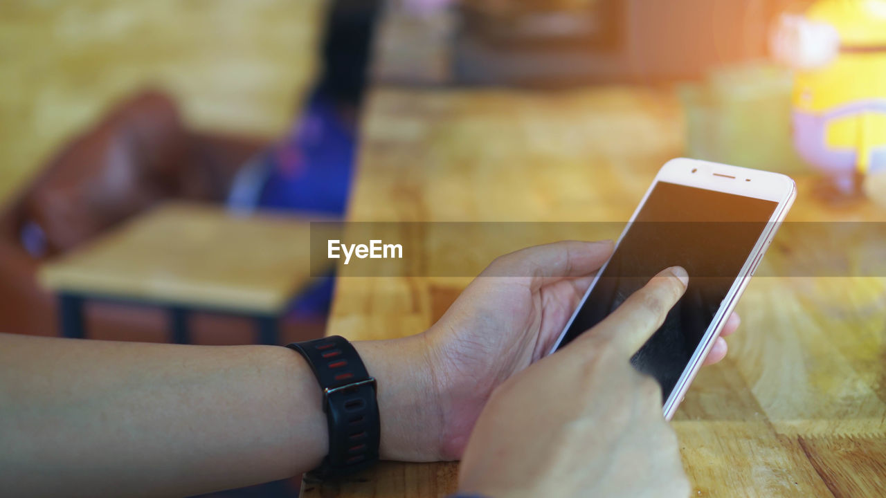 Cropped hands of man using mobile phone on table