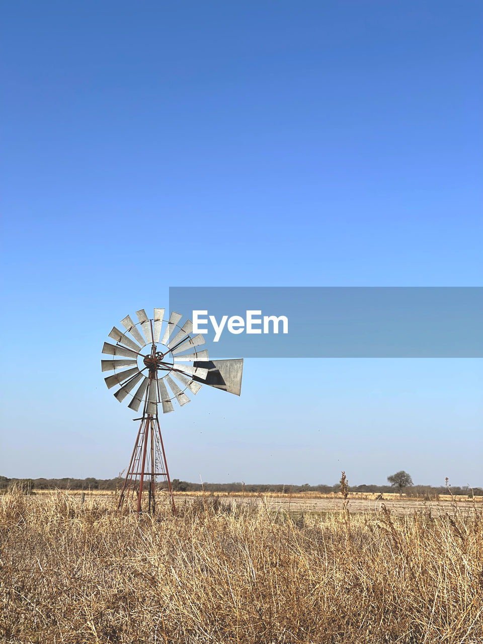 low angle view of umbrella on field against clear blue sky