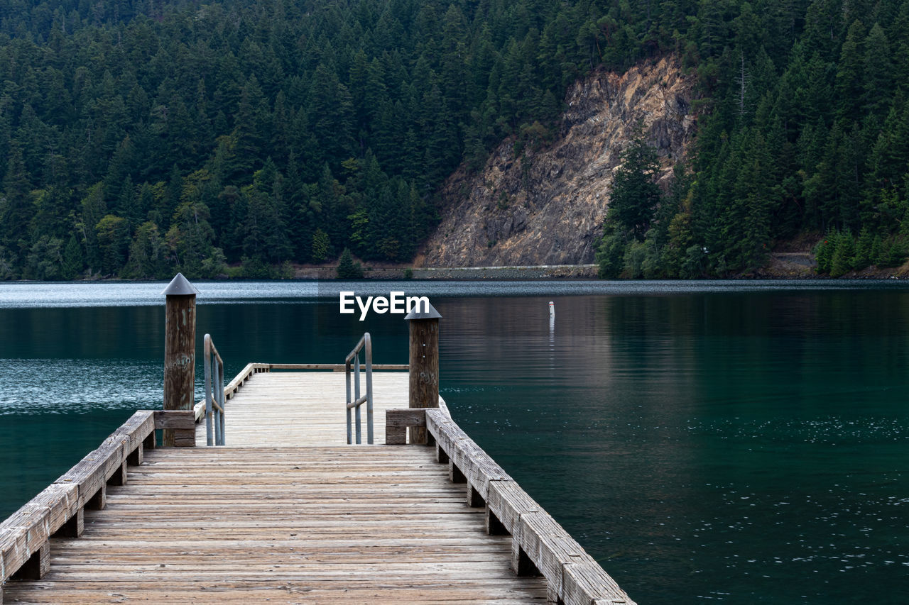 Pier over lake against trees and mountains